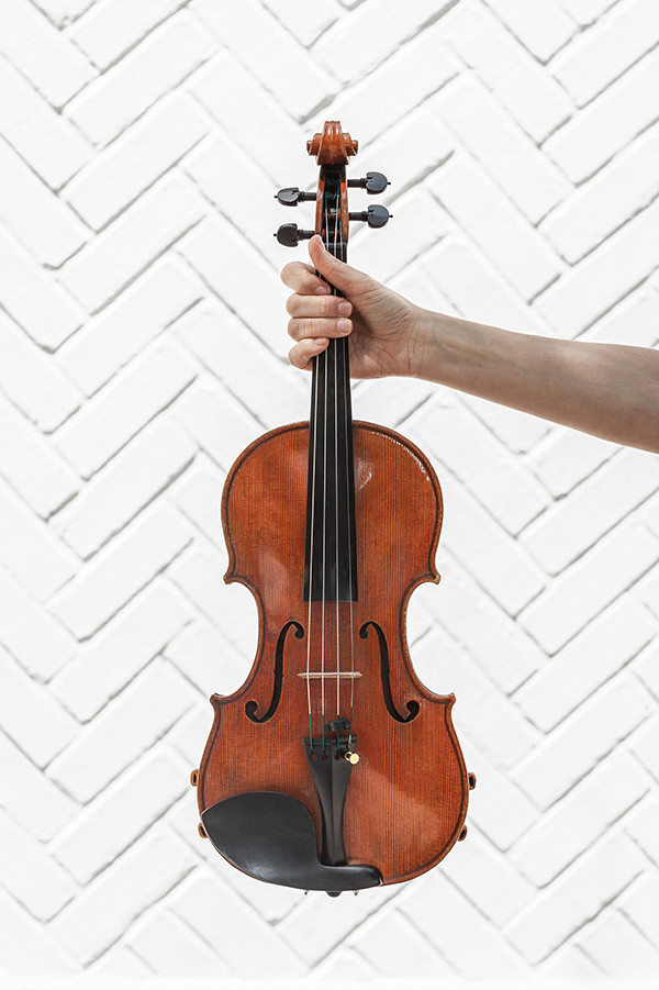 Hand with violin in front of a white wall
